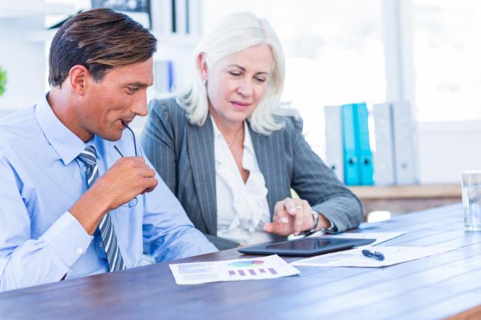 two financial advisors look at tablet and financial graphs in office financial advisor transitions